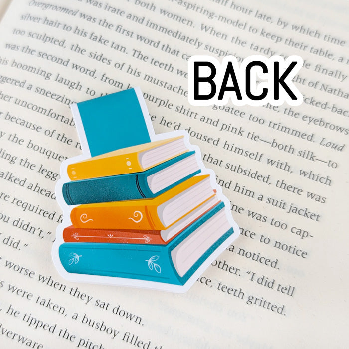 Magnetic bookmark featuring a colorful stack of books with plain spines laying on an open book. The word "back" indicates the back of the bookmark.