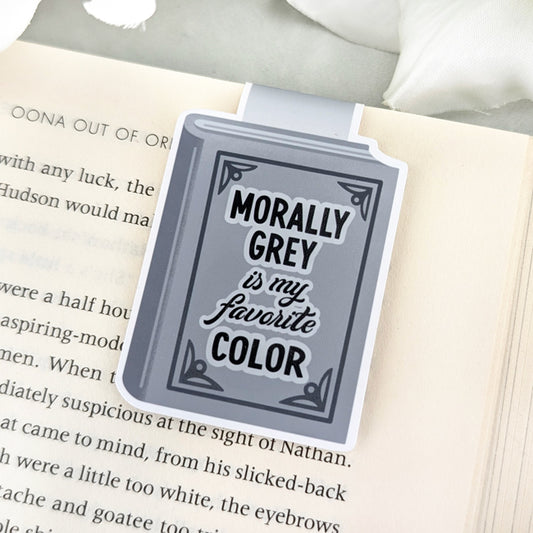 Magnetic bookmark shaped like a grey book with the phrase "Morally Grey is My Favorite Color" in bold lettering, clipped to an open book.