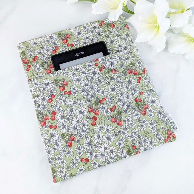 Maxi book sleeve with a soft green background and a delicate print of white daisies and red strawberries, displayed with white flowers.