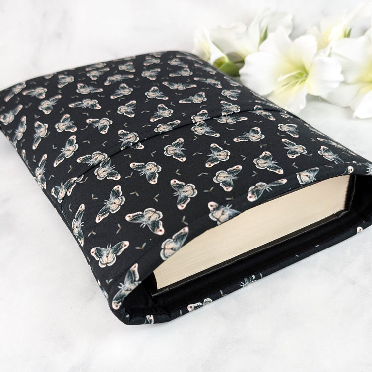 Black book sleeve with a delicate moth pattern in soft gray and cream tones, creating an elegant nocturnal aesthetic.