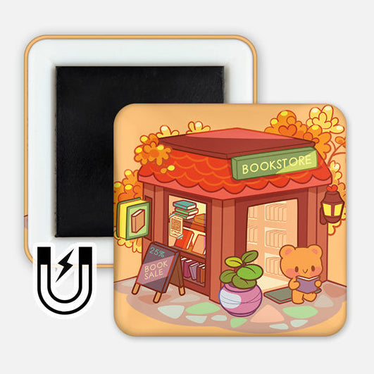 Square 2x2" magnet with a warm autumn color palette, featuring a cute illustrated bear standing in front of a cozy bookstore with a red roof, potted plant, and a “25% Book Sale” sign. Magnetic backing is partially visible.