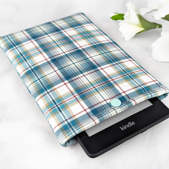 padded Kindle sleeve with snap, fabric features plaid pattern in shades of teal, white and gray.