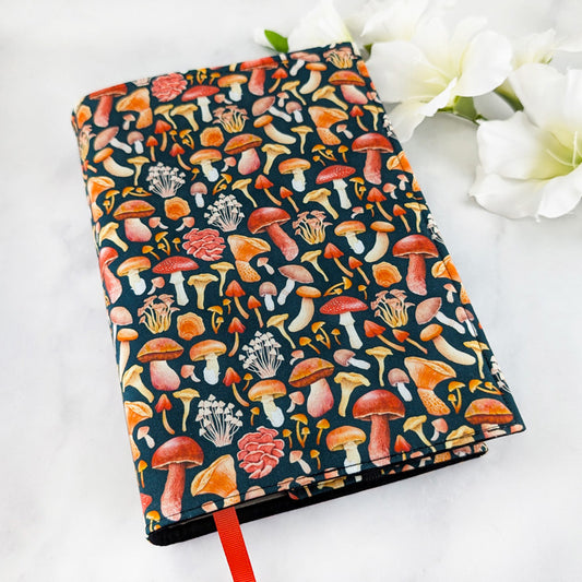 adjustable fabric book cover, fabric pattern showcases variety of fall mushrooms on a dark navy background.