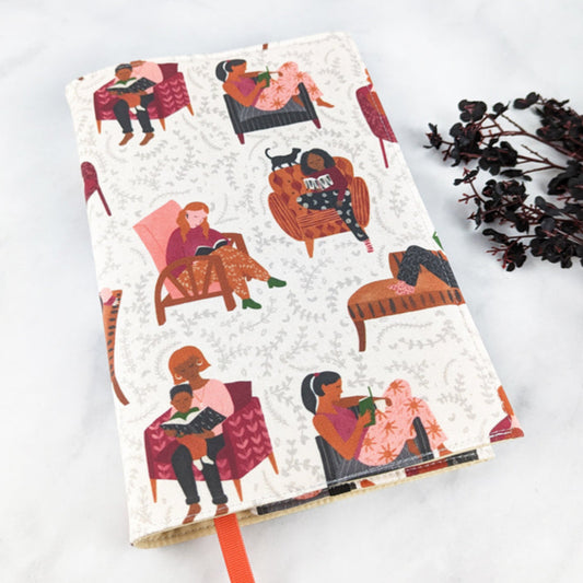 Fabric book cover featuring a cozy reading theme with illustrated people lounging in chairs and reading books, set against a soft cream background with subtle vine-like patterns, finished with an orange ribbon bookmark.
