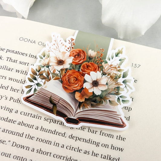 magnetic bookmark featuring a bouquet of orange and white flowers spilling out from the pages of an open book.