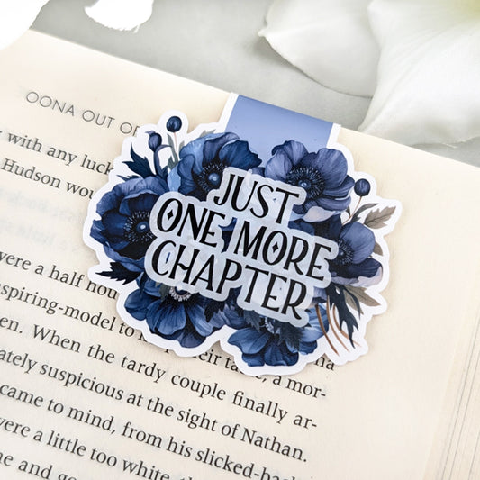 Magnetic bookmark featuring navy blue anemone flowers and the phrase 'Just One More Chapter,' clipped to an open book.