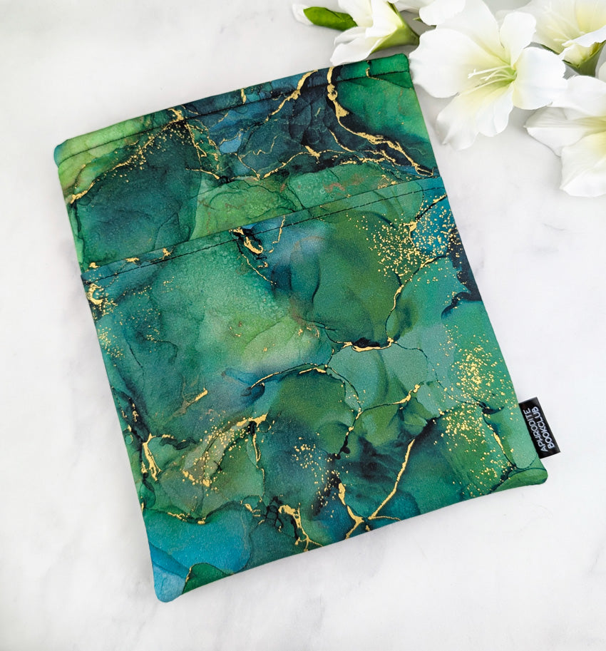 large padded book sleeve with pocket. fabric showcases green and teal marble texture with gold accents.