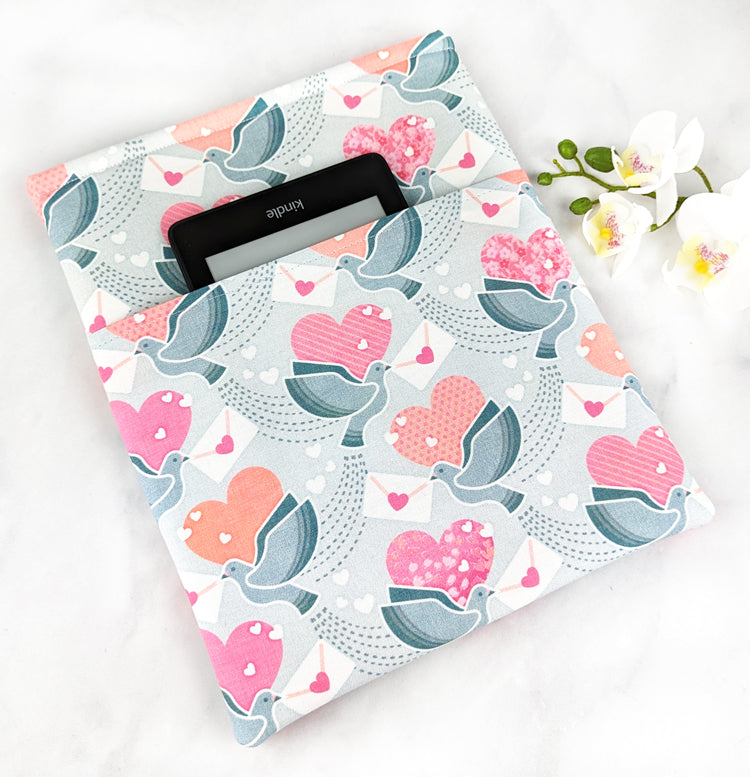 Book sleeve with a soft grey background featuring white doves holding envelopes with pink hearts, surrounded by pink and red heart shapes and dotted trails.