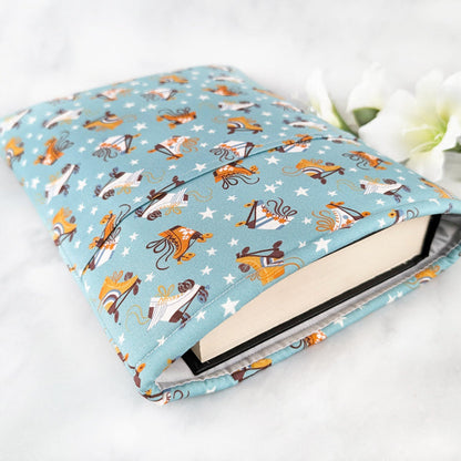 large padded book sleeve with pocket. fabric showcases orange and white roller blades and tiny white stars on a dusty blue background.