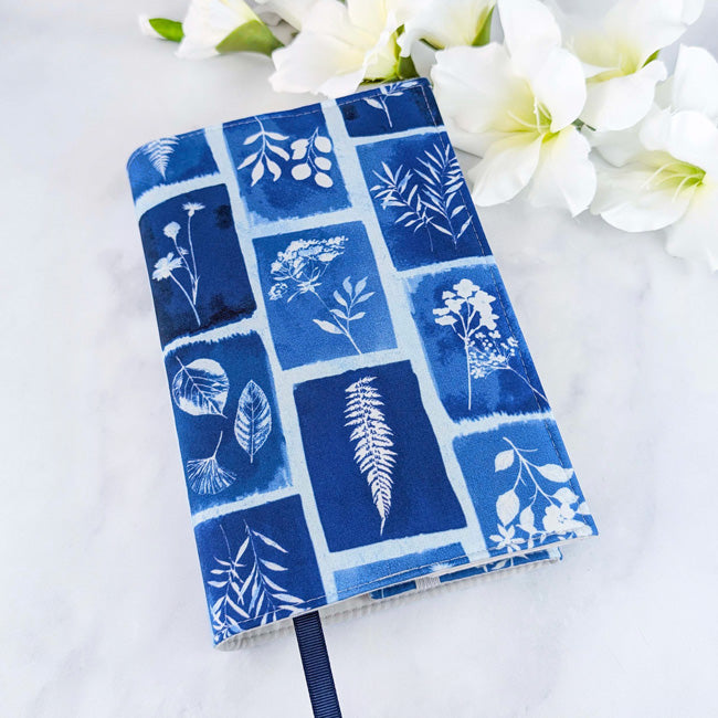 Medium book cover with a blue and white botanical print resembling cyanotype art, featuring various leaves and flowers in rectangular frames, styled with white flowers.