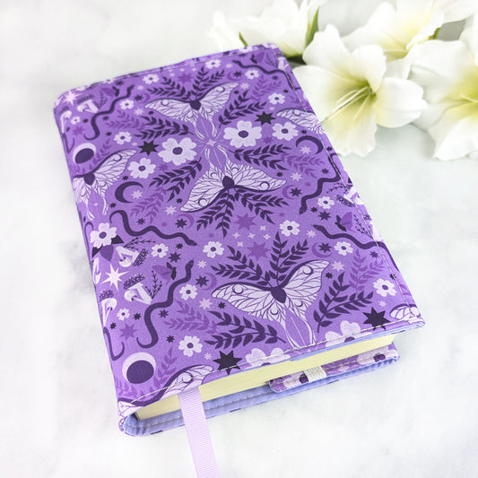 Lavender purple book cover with a celestial moth and floral pattern featuring moons, stars, vines, and blossoms in deep violet tones.