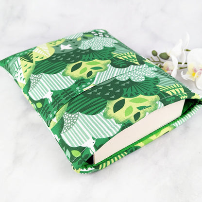 medium padded book sleeve with pocket. fabric showcases whimsical foresty hills with white birds and rabbits hidden throughout.