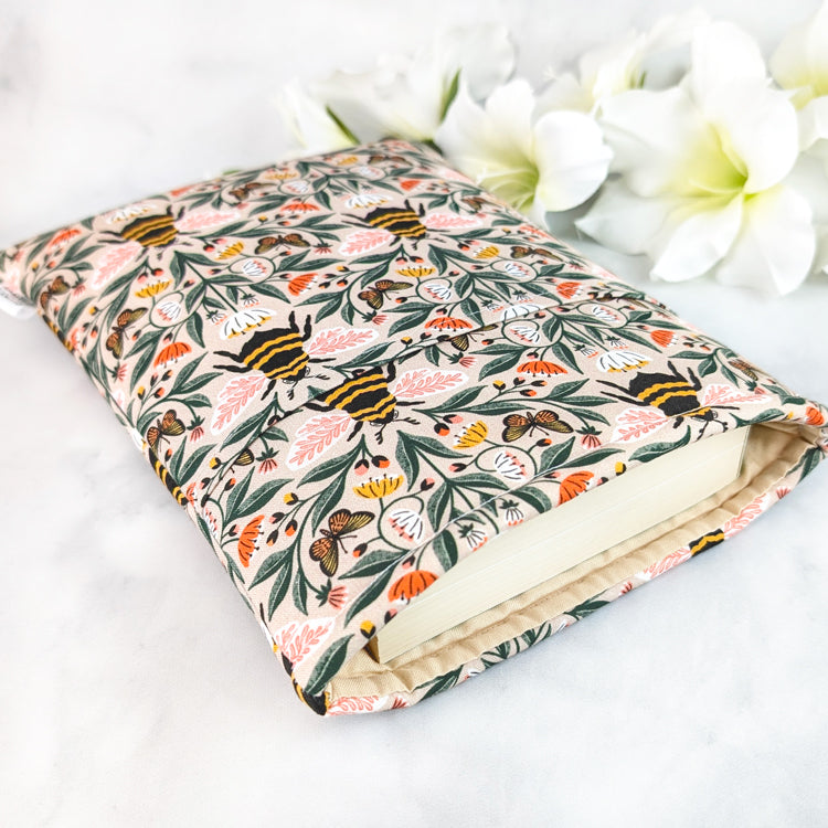 Beige book sleeve with a floral bee pattern featuring orange, yellow, and pink wildflowers on leafy vines.