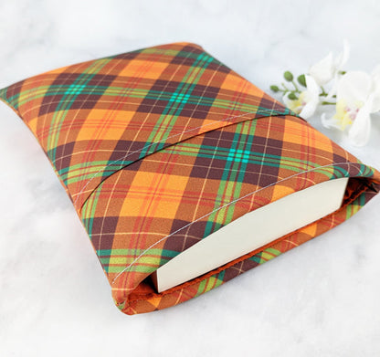 medium padded book sleeve with pocket. fabric features plaid pattern in shades of orange, green and brown.