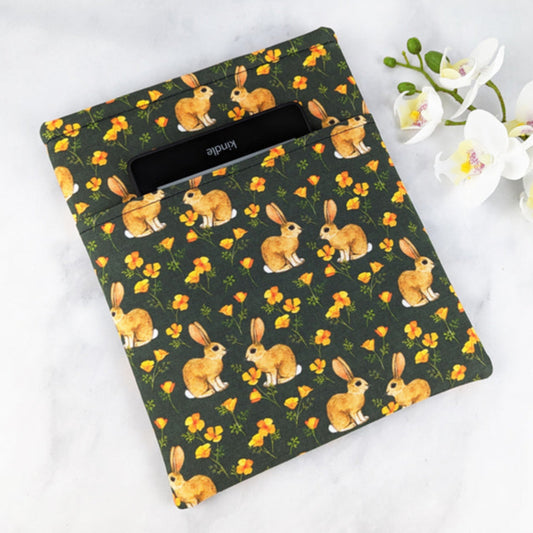 medium padded book sleeve with pocket. fabric features rabbits, California poppies on a dark green background.