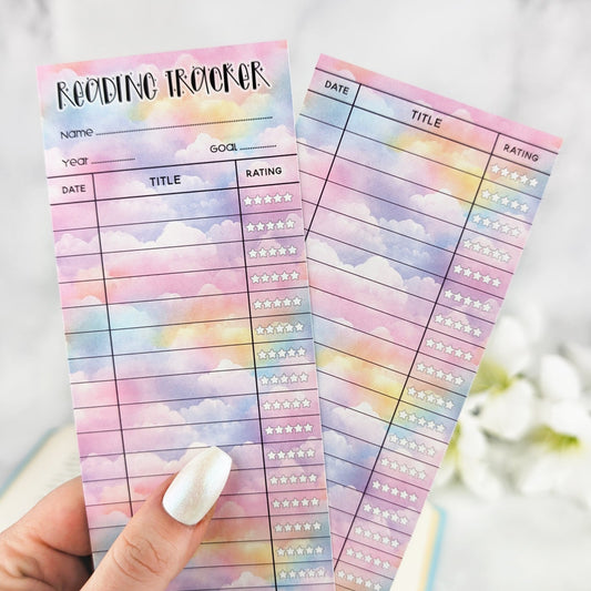 hand holding two bookmark reading trackers, one showing front and one the back. bookmark has a pastel cloud background and the table to track and rate books read.