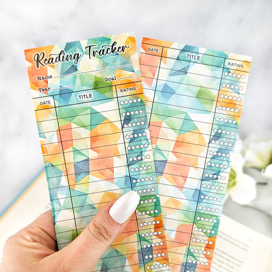 hand holding two bookmark reading trackers, one showing front and one the back. bookmark has a geometric background in green, orange, yellow colors, and the table to track and rate books read.