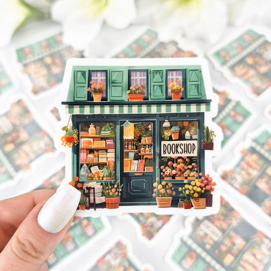 Illustrated sticker featuring a cozy bookshop with green shutters, flowers, and books on display.