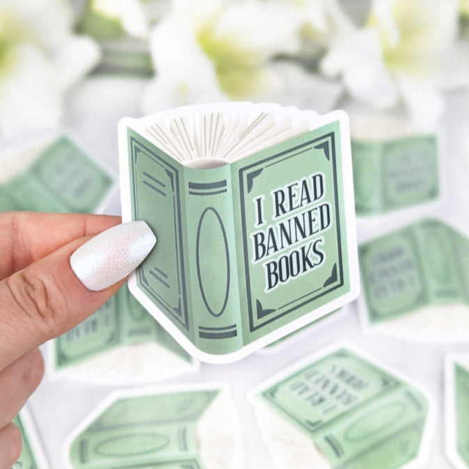 Drawn sticker of a sage green book with the text "I Read Banned Books" in a vintage style.