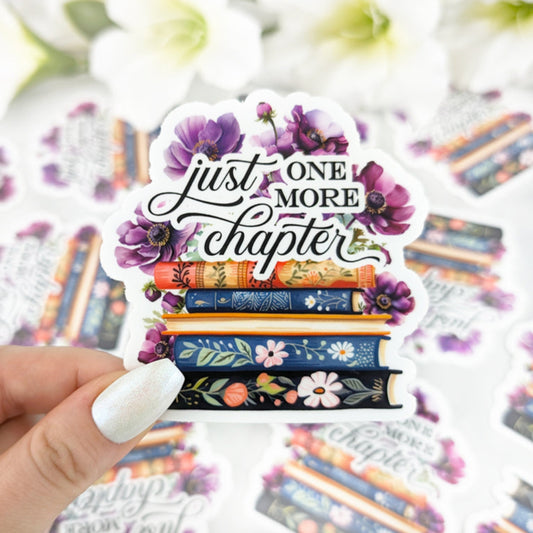 Illustrated sticker featuring a stack of vintage-style books adorned with flowers and the phrase "Just One More
Chapter" in elegant calligraphy.