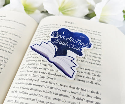 Read All Night Book Club vinyl sticker featuring an open book with starry night sky design, placed on the pages of a novel.